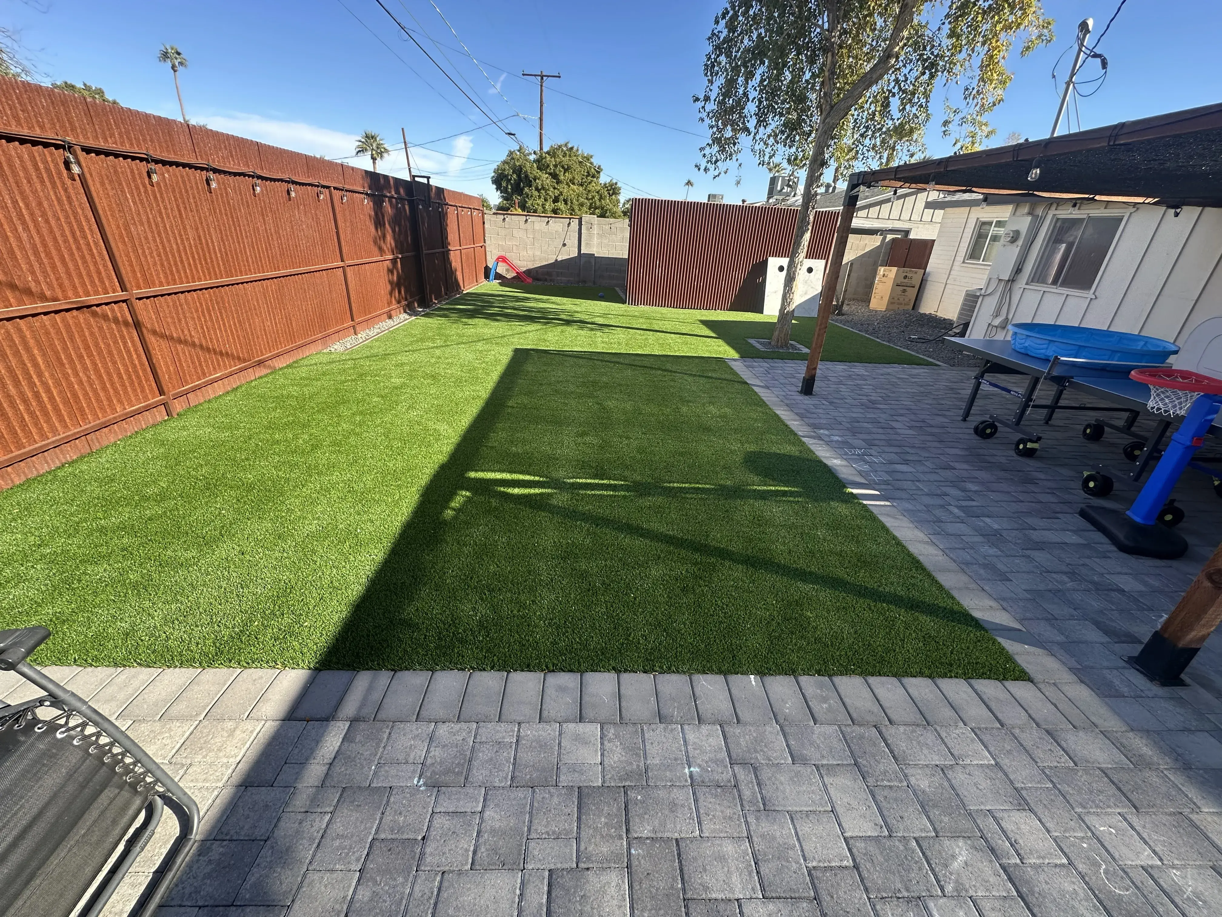 After: Backyard transformation with artificial grass and extended paver patio